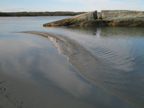 small wave crashing onto the sandy beach